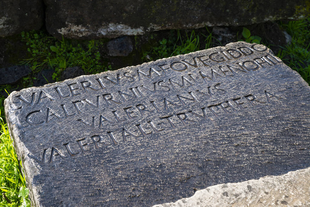 Inscription d'une tombe sur l'ancienne Appia di Valerius rayonnée par les rayons du soleil après la tempête immergée dans la verdure sur l'Appia Antica près de la Villa de Maxence. Rome Italie Europe. - Photo, image