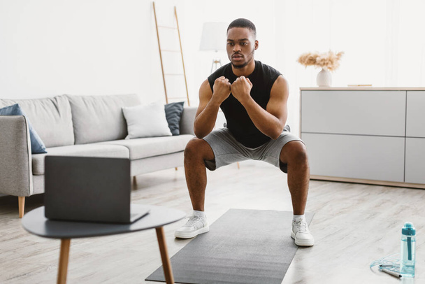 Athletic African American Guy Doing Squats At Laptop At Home - Photo, Image