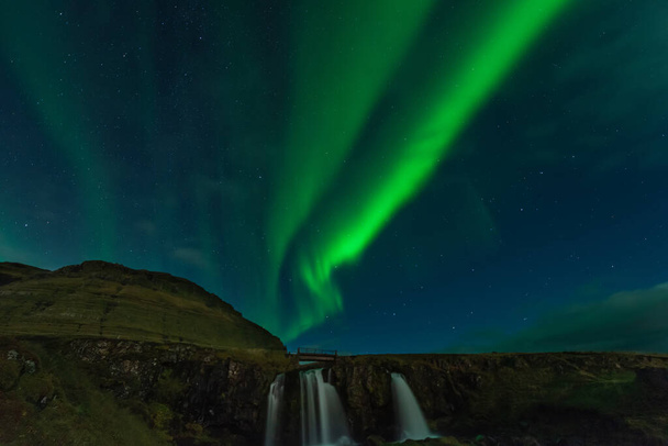 アイスランドの北の光。kp5オーロラボレアリスでいっぱいの風景。カークジュフェル、風光明媚な旅行先で素晴らしい夜景。星でいっぱいの緑の空. - 写真・画像