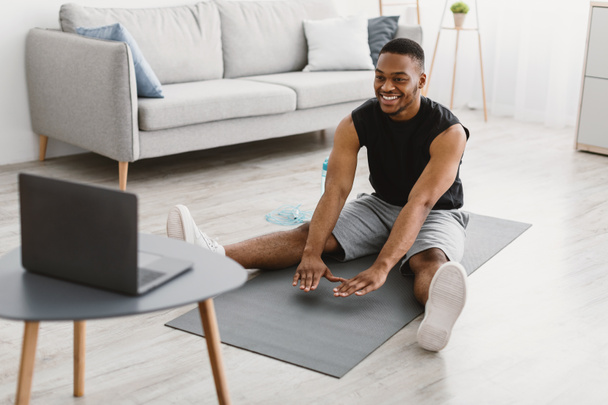 Black Man Doing Stretching Workout Exercise At Laptop At Home - Foto, Imagem