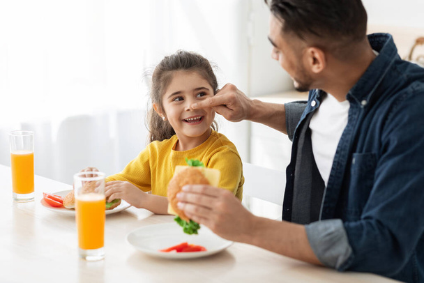 Portret wesołego arabskiego taty i małej córeczki jedzącej lunch w kuchni - Zdjęcie, obraz