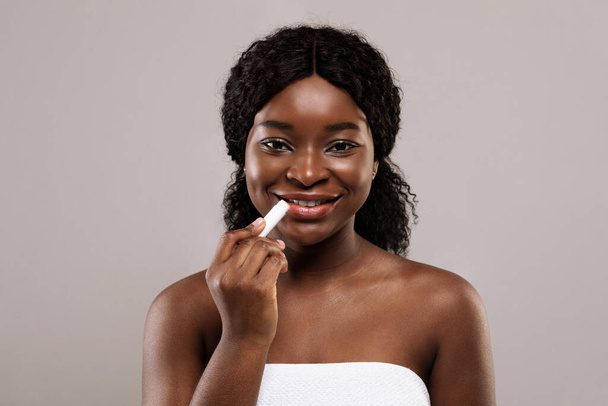 Prevenção de lábios rachados. bela preto senhora usando Chapstick e sorrindo para câmara - Foto, Imagem