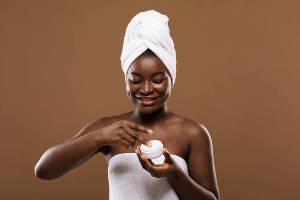 Anti-Aging Treatment. Smiling Black Female With Towel On Head Applying Moisturising Cream - Photo, Image
