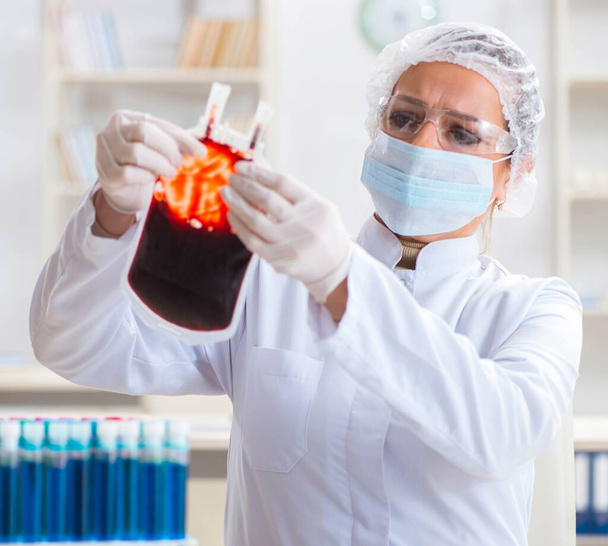 Vrouwelijke arts controleert bloedmonsters in het lab - Foto, afbeelding