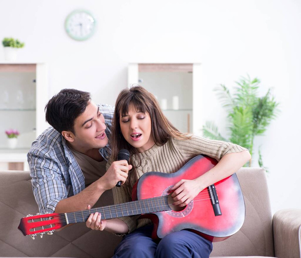 Joven familia cantando y tocando música en casa - Foto, imagen