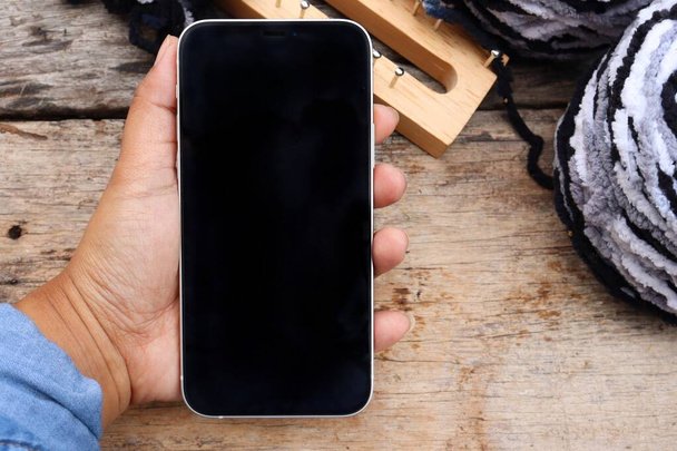 Telefone inteligente na mão com rolo de bola de fio cinza e branco - Foto, Imagem