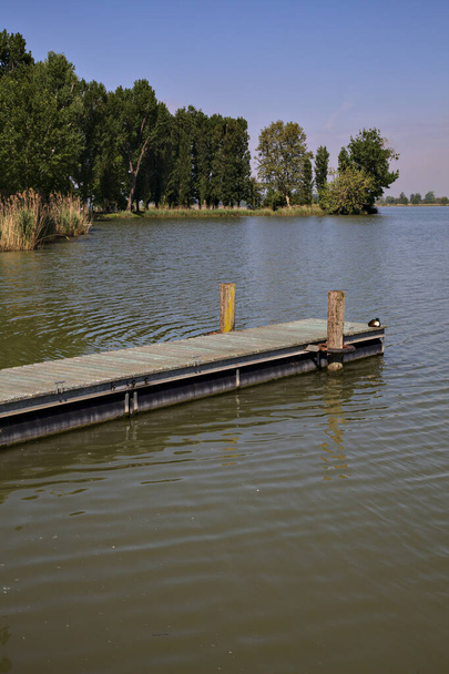 Liegeplatz an einem Fluss mit einem Ufer, das sich im Hintergrund erstreckt - Foto, Bild