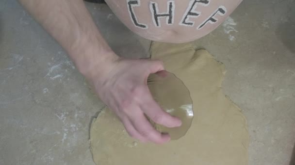 Товстий хлопець зі словом шеф-кухаря на животі кладе його тертим сиром в тісто
 - Кадри, відео