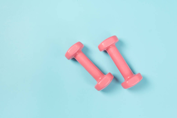 Two pink dumbbells isolated on blue background - Foto, immagini