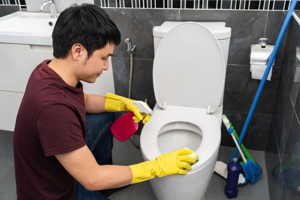 young man cleaning toilet bowl in bathroom - 写真・画像