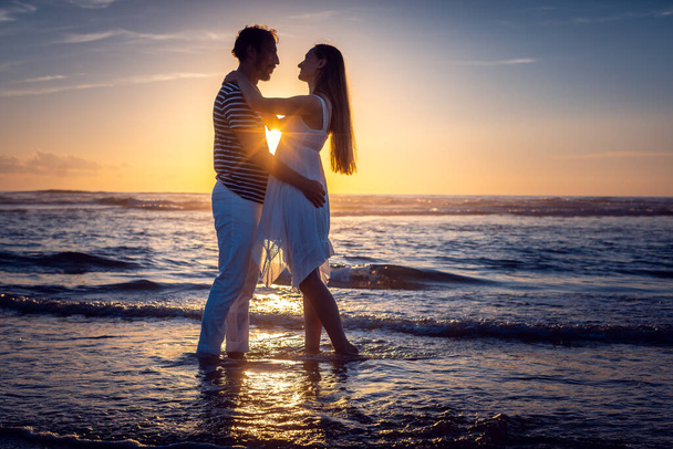 Pareja romántica enamorada besándose en la playa al atardecer - Foto, imagen