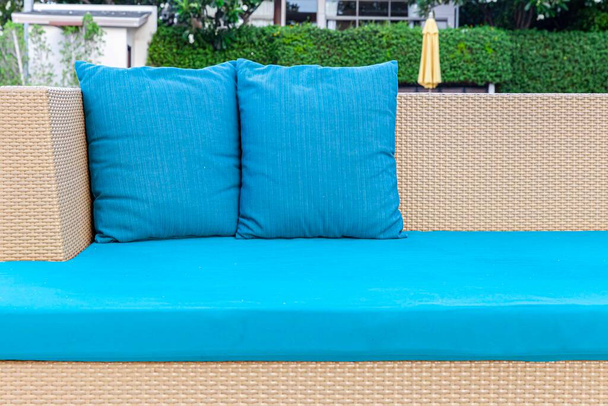 Μακρύ καφέ καναπέ λυγαριά και μπλε μαξιλάρια και μαξιλάρια τοποθετούνται στο γκαζόν - Φωτογραφία, εικόνα