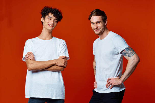 funny two men in white t-shirts on a red background friendship - Valokuva, kuva