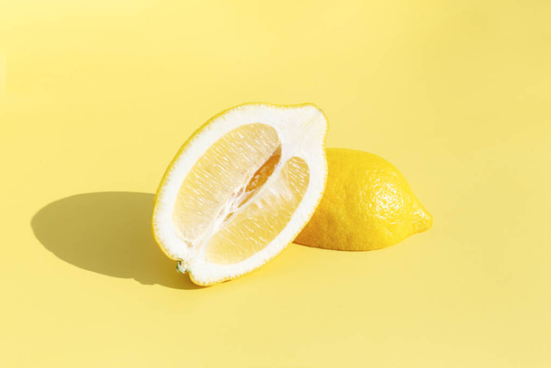 Two halved cuts of lemon with shadow on yellow background. Healthy eating, travel or vacation concept - Photo, Image