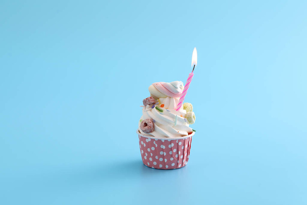 Colorful cupcake with candle isolated in blue background - Photo, Image