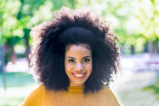 Портрет милої і щасливої дівчини з афро в саду. крупним планом
. - Фото, зображення