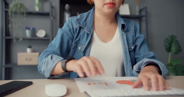 Szabadúszó ázsiai hölgy alkalmi viselet segítségével asztali számítógép online tanulni a nappaliban a házban. Otthonról való munkavégzés, távoktatás, társadalmi távolság, karantén a koronavírus megelőzése érdekében. - Felvétel, videó