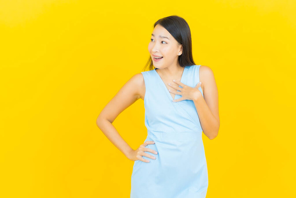 Portrait beautiful young asian woman smile with action on yellow color background - Photo, Image