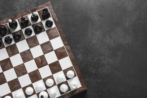 Piezas de ajedrez con tablero de juego sobre fondo oscuro - Foto, Imagen