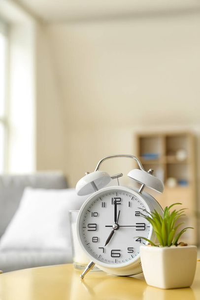 Alarm clock and houseplant on table in room - Fotoğraf, Görsel
