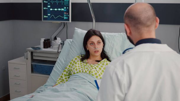 Κλείσιμο της άρρωστης γυναίκας με ρινικό σωλήνα οξυγόνου που αναπαύεται στο κρεβάτι - Φωτογραφία, εικόνα