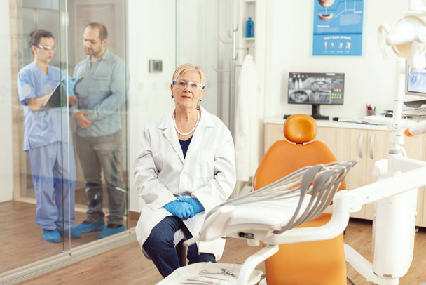 Portret uśmiechniętej starszej dentystki w gabinecie stomatologicznym - Zdjęcie, obraz
