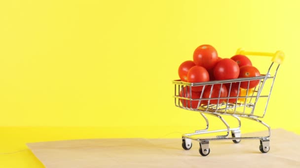 Nákupní košík s cherry rajčaty uvnitř na žlutém pozadí, detailní záběr. Černý pátek Nákupní a slevy koncept - Záběry, video