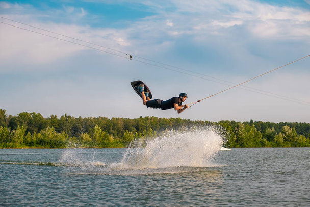 maschio wakeboarder esecuzione saltando sopra acqua creando spruzzi - Foto, immagini