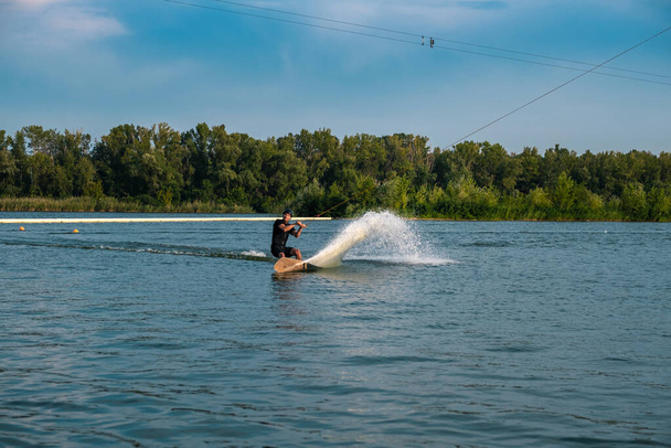 Homme sportif chevauchant sur wakeboard sur la rivière le jour de l'été - Photo, image