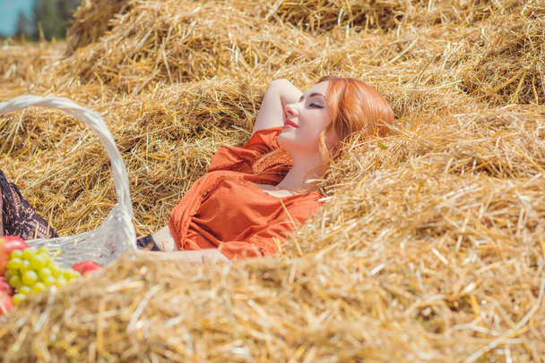Country vintage mix stijl, vrouw met mand van fruit op het veld. Portret van een aardige dame op hooizolder - Foto, afbeelding