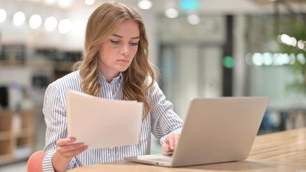 Serious Businesswoman with Laptop Reading Documents in Office - Photo, Image