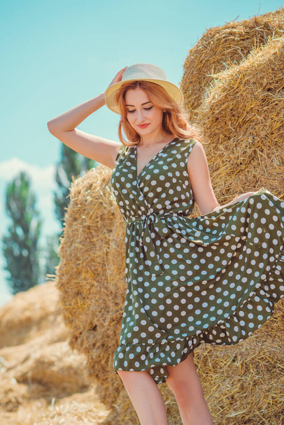 Country vintage mix style, nice redhead woman . Portrait of nice lady at hayloft. Woman in green polka dot dress and hat. Fashion concept - Fotó, kép