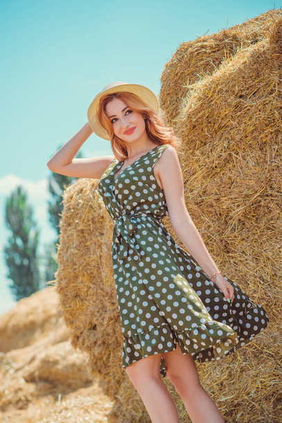 Country vintage mix style, nice redhead woman . Portrait of nice lady at hayloft. Woman in green polka dot dress and hat. Fashion concept - Photo, Image