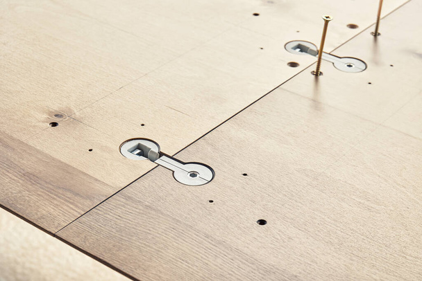 Assembling of large wooden dining table with installed worktop connectors and screws outdoors on sunny day extreme close view - Φωτογραφία, εικόνα