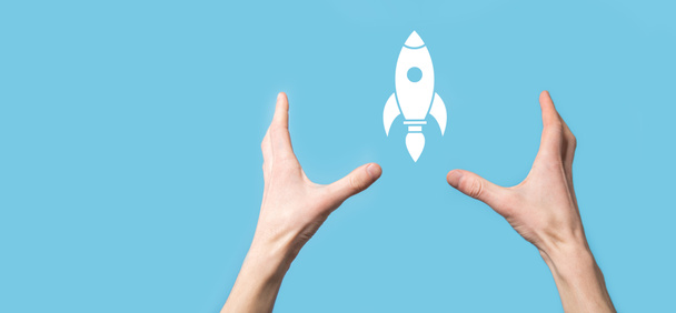 Male hand holding rocket icon that takes off, launch on blue background. rocket is launching and flying out, Business start up, Icon marketing on modern virtual interface.Start up concept - Foto, immagini