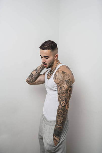 A vertical shot of a good looking tattooed young European man with white background - Photo, image