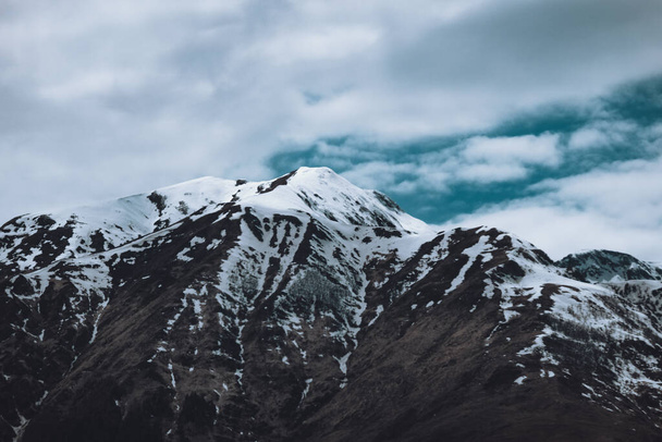 A majestic view of snowy mountains under a cloudy sky - Foto, afbeelding