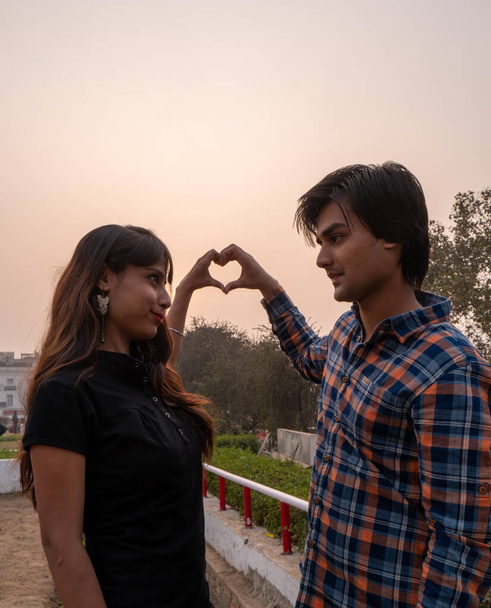 A beautiful Indian couple making a heart with their hands and looking at each other - Foto, Imagen