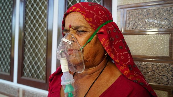 Женщина, страдающая болезнью Ковида 19. Старуха, госпитализированная в больницу и вдыхающая кислород с маской из канулы. - Фото, изображение