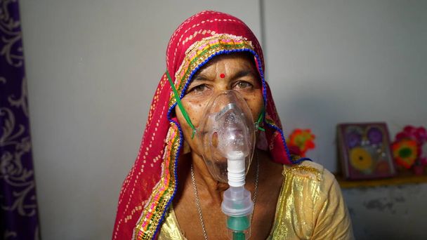 Mujer con enfermedad de Covid 19. Mujer anciana ingresada en el hospital e inhalando oxígeno de emergencia con máscara de canula. - Foto, Imagen