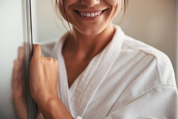Happy cheerful pretty female in white bathrobe posing at the photo camera in spa salon - Zdjęcie, obraz