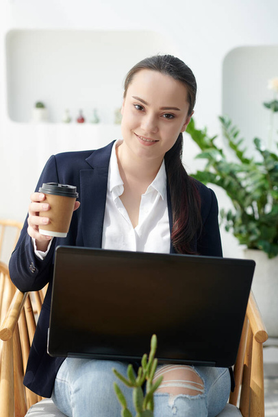 Usmívající se hezká vysokoškolačka pití kávy a práci na notebooku v jídelně - Fotografie, Obrázek