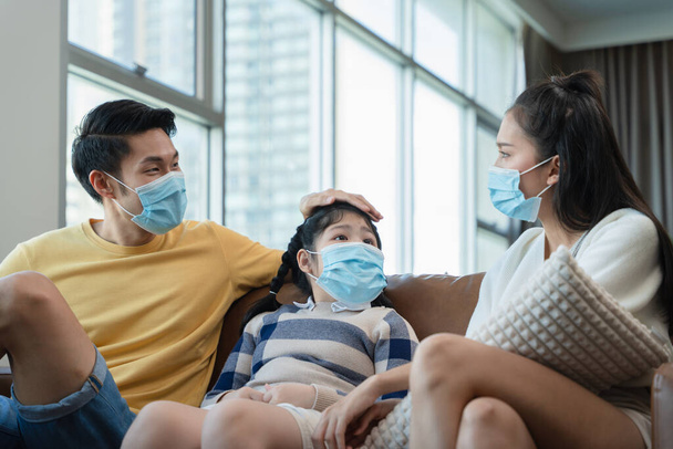 Asian family spending time together at home while wearing face mask. precaution to prevent coronavirus by wearing protective mask. - Zdjęcie, obraz