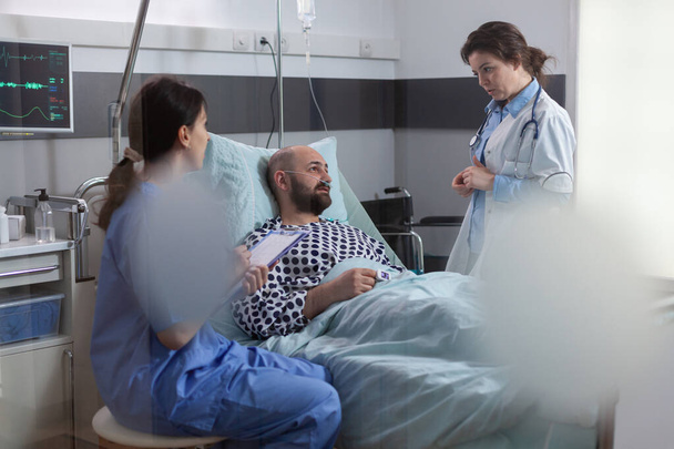 Zespół medyczny monitoruje chorego człowieka wyjaśniając objawy choroby - Zdjęcie, obraz