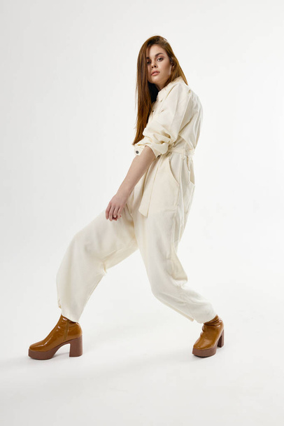 kobieta w brązowych butach biały kombinezon studio mody lekkie tło - Zdjęcie, obraz
