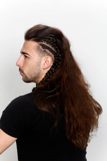 Стильна чоловіча модель з косами позує в студії на ізольованому фоні. Стиль, зачіска, концепція моди
. - Фото, зображення