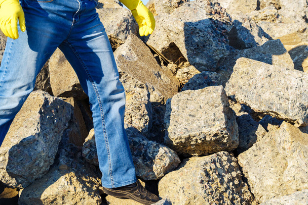 een man werkt met een stapel stenen en gebroken stukken beton, draagt bouwpuin - Foto, afbeelding