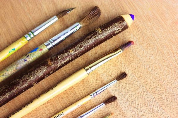 塗装ブラシのセットは、木製の表面に紫色の棒を上から見た木製の鉛筆、フラット。幼稚園、学校、大学、趣味のクラスのためのツール。もう一度学校に戻る概念。美術.  - 写真・画像