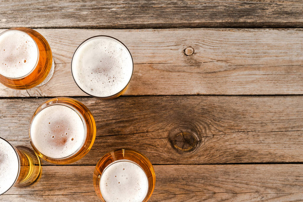 Overhead shot of beer glasses on wooden table. - Foto, afbeelding