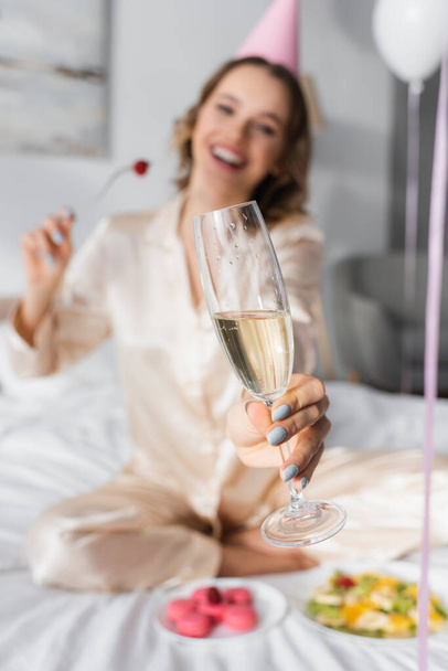 Blurred woman holding glass of champagne while celebrating birthday in bedroom  - Foto, Imagem